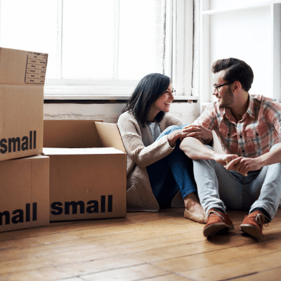 Couple relaxing amongst cardboard moving boxes while moving into new flat